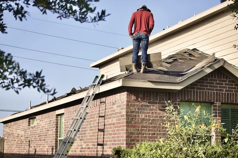 Professional roofer working on a residential roof in Queens Guard